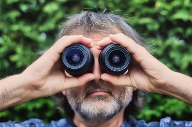Man with photo lenses in front of his eyes as if he were binoculars