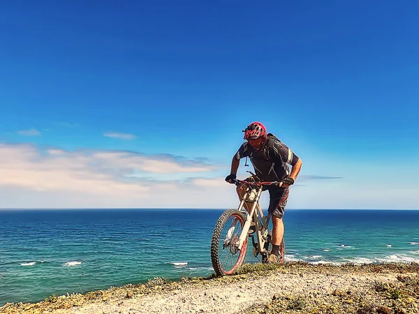 Okyanus kıyısında kask eğitimi almış bir bisikletçi.