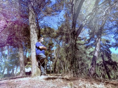 Yetişkin bir adam yaz günü şehir parkında yürüyor.