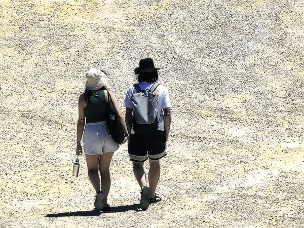 Kumsalda yürüyen bir çift turist.