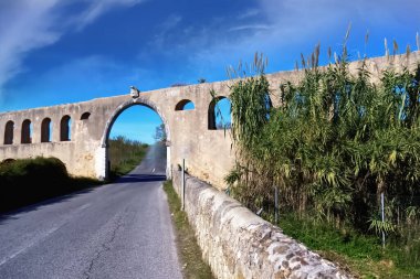 Güneşli bir günde mavi gökyüzü ve beyaz bulutlarla eski taş köprü
