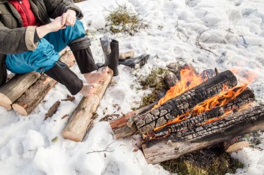 Karla kaplı orman yangın yakındaki bir adam ısıtır 