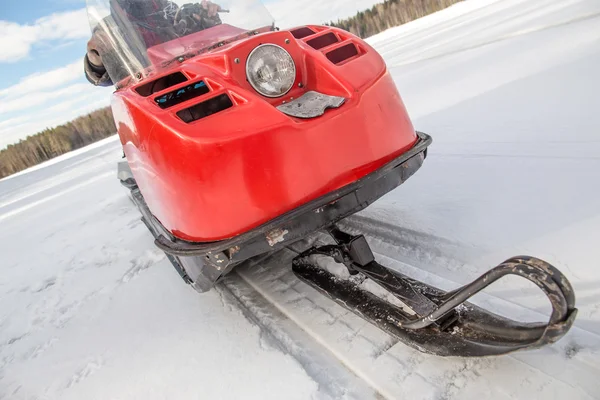 Un uomo a cavallo vecchia motoslitta rossa sul lago innevato — Foto Stock