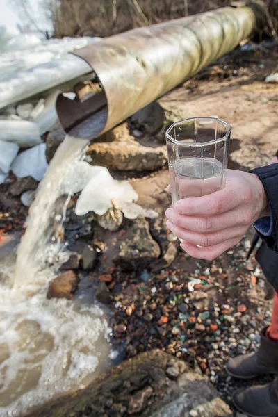 A man stands with a glass filled with water from sewer