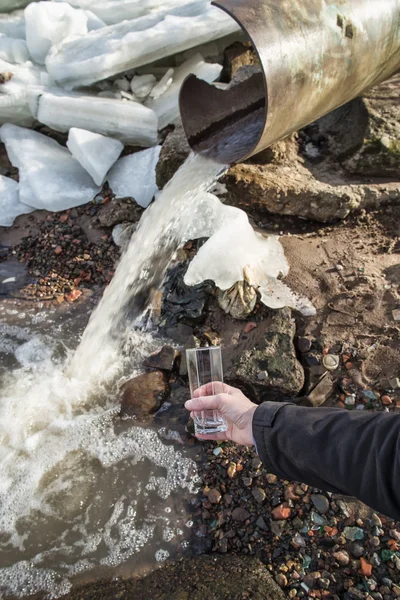 En man står på avloppet med ett tomt glas i handen — Stockfoto