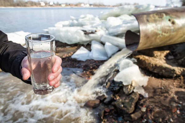 En man står med ett glas vatten från avlopp — Stockfoto