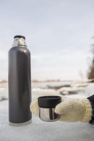 Mann hält eine Tasse heißen Tee aus einer Thermoskanne in der Hand — Stockfoto