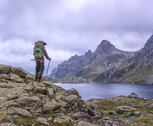 Mann mit Vintage-Rucksack steht auf dem Hintergrund des Berges — Stockfoto