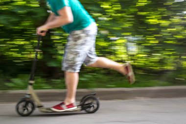 adam bir scooter yolun aşağısında, arka plan bulanık hızda sürmek