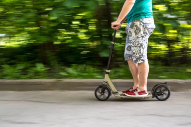 adam bir scooter yolun aşağısında, arka plan bulanık hızda sürmek