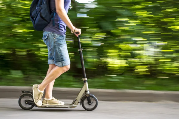 Female rides a scooter at speed down the road, blurred backgroun — Stock Photo, Image