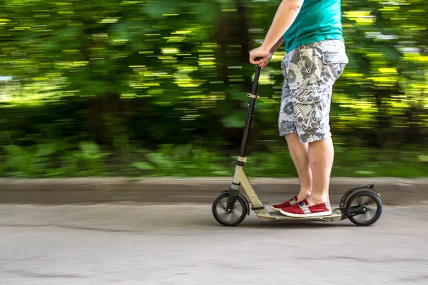 Man rides a scooter at speed down the road, blurred background — Stock Photo, Image