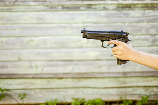 Child's hand with a gun, isolated on old wall background, closeu — Stock Photo, Image