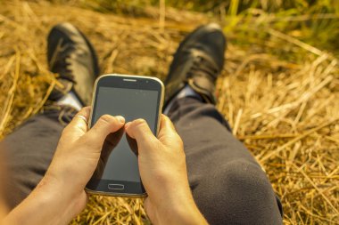 saman üzerinde oturan kız ve cep telefonu tutar