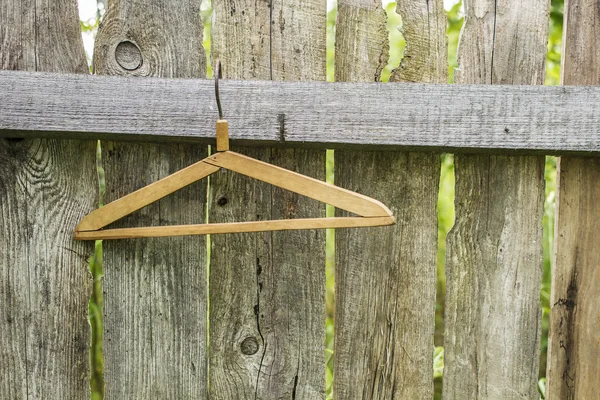 Wooden a hanger hanging in an old fence from boards — Stock Photo, Image