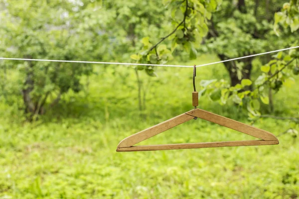 Alter hölzerner Kleiderbügel hängt im Garten am Seil — Stockfoto