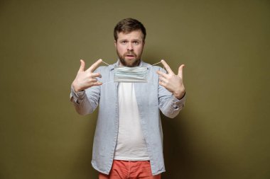 Kafası karışmış bir adam birine tıbbi maske teklif eder ya da kendisi takar. Salgın sırasında sağlık ve güvenlik kavramı.