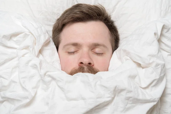Милый, очаровательный мужчина спит завернутый в одеяло. — стоковое фото