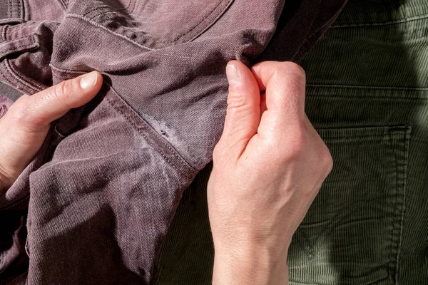 Woman hands are holding the old worn out, torn trousers. Close-up. — Stok fotoğraf