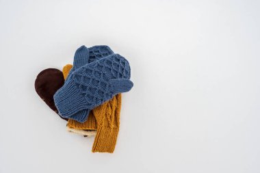 Birkaç çift örülmüş, sıcak eldiven bulutlu bir kış gününde beyaz ve temiz kar üzerinde bir yığın halinde yatar. Boşluğu kopyala. 