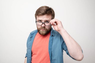 Ciddi ve çekici bir adam kameraya bakıyor, elleriyle bardakları tutuyor. Beyaz arkaplan.