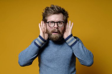 Garip kıllı adam bir şeyler yapmaya çalışıyor. Kulak misafiri olmuş ve yüzünde tuhaf bir ifade var. Kameraya bakıyor..