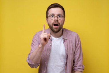 Harika bir fikir. Gözlüklü yakışıklı adam işaret parmağını kaldırıyor, kameraya ağzı açık bakıyor ve ilginç bir yüzü var.. 