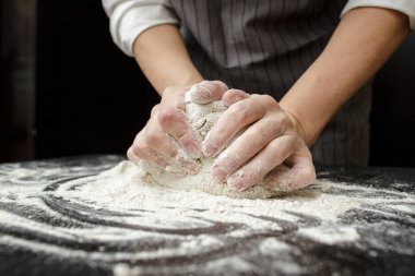 Fırıncının güçlü elleri un kaplı bir masada hamur yoğurur. Ekmek yapma.