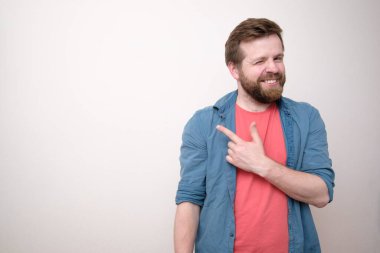 Pozitif, gülümseyen adam işaret parmağını yana doğrultuyor ve onaylayıcı görünüyor. Uzayı kopyala Beyaz arkaplan.