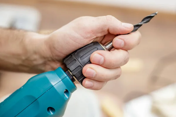 Мужская рука устанавливает стальной бит в электрическую дрель. Подготовка инструмента для работы. — стоковое фото