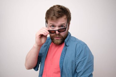 Kafkasyalı, sakallı bir adam gururla güneş gözlüklerinden bakıyor. Beyaz arkaplan.