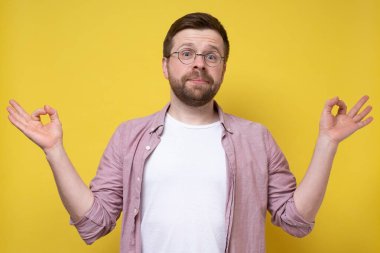 Gözlüklü komik sakallı adam meditasyon yapıyor, uyum ve dengeyi bulmaya çalışıyor, başparmağını ve işaret parmağını birleştiriyor ve yardımsever görünüyor.. 