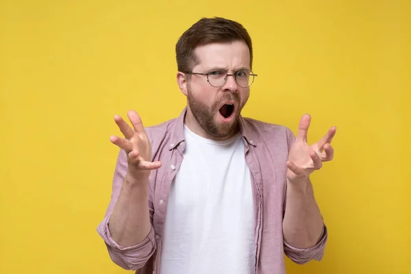 Disgruntled, aggressive Caucasian man in glasses accuses someone, he swears and indignantly gesticulates with hands. — Stock Photo, Image