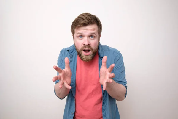 Disgruntled, annoyed bearded man looks inquiringly with mouth open and makes a surprised gesture with hands. White background. — Stock Photo, Image