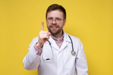 Sakin, yardımsever doktor işaret parmağını kaldırdı, soruna bir çözüm buldu ve çok mutlu. Sarı arkaplan.