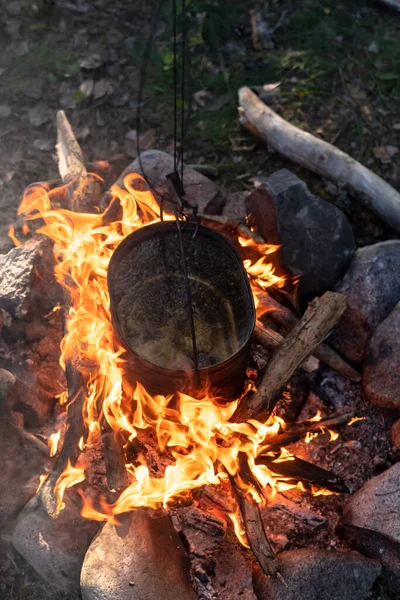 Μια κατσαρόλα με βραστό νερό κρέμεται πάνω από μια φωτιά. Μαγείρεμα στο στρατόπεδο. Ενεργός τρόπος ζωής. — Φωτογραφία Αρχείου