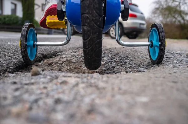 Bicicleta infantil con ruedas pequeñas en los laterales para un paseo seguro, sobre el fondo del coche. Primer plano. —  Fotos de Stock