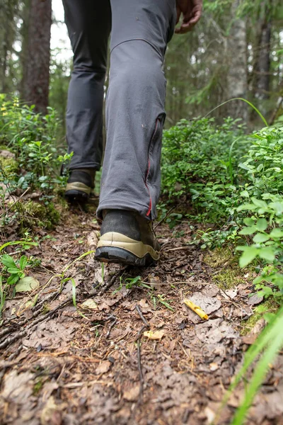 Männliche Füße in Stiefeln laufen auf einem Waldweg vor dem Hintergrund von Bäumen. Tourismus und aktiver Lebensstil. — Stockfoto