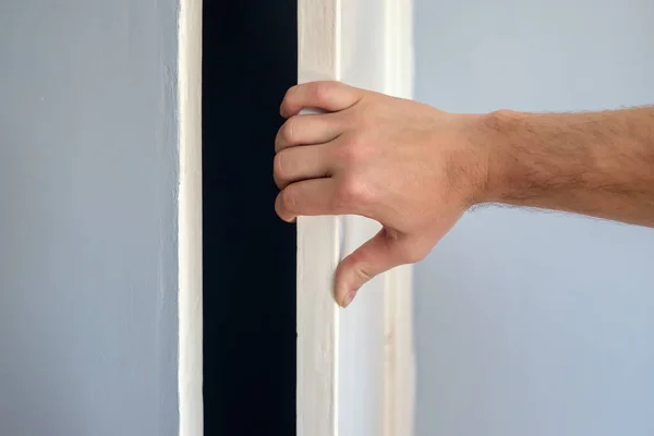 Mão de homem abre a porta branca de um armário azul. — Fotografia de Stock