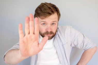 Sakin, kendine güvenen bir adam dur işareti yapar, avucunu ileri uzatır ve kameraya ciddi ciddi bakar.. 