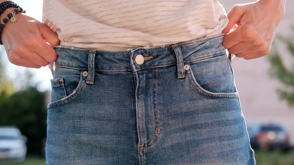 Mulher segura os shorts com as mãos, ela perdeu peso seguindo uma dieta e as roupas se tornaram grandes para ela. Estilo de vida. — Fotografia de Stock