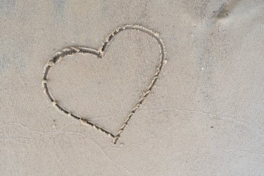 Sıcak bir yaz gününde kumlu bir nehir kıyısına kalp sembolü çizilmiş. Tatil aşkı. Yaşam tarzı. Uzayı kopyala Üst görünüm.