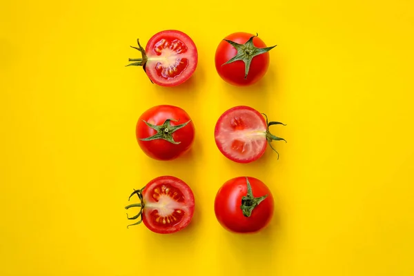 Red tomatoes, whole and sliced, isolated on a yellow background. Beautiful picture. Top view. — Stock Photo, Image