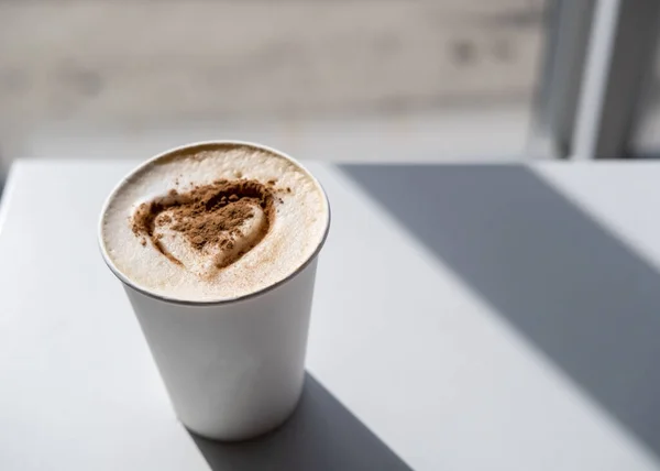 Cappuccino dengan kayu manis dan hati dicat pada busa subur, dalam sinar matahari. menyegarkan, aroma minuman pagi. Salin ruang. — Stok Foto
