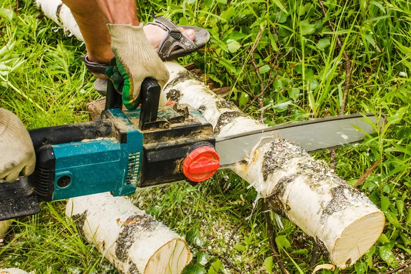 Homem serrar madeira, usando motosserras elétricas — Fotografia de Stock