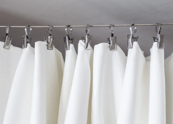 Cream-colored curtain hanging on a string on metal hooks illuminated by daylight — Stock Photo, Image