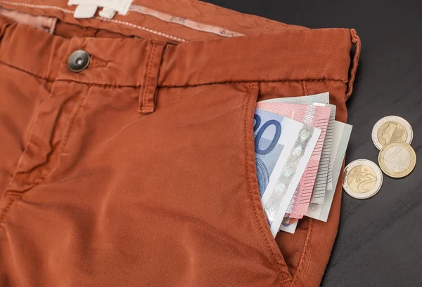 Euro-Papiergeld ragt aus seiner Hosentasche und eine Münze auf dem Tisch — Stockfoto