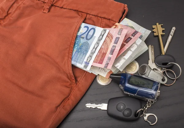 Euro money and coins fell out of his pocket on the table, on which lie the keys — Stock Photo, Image
