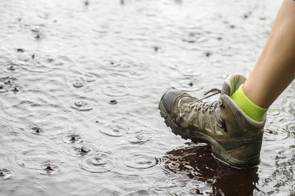 Pessoa em botas de caminhada andando sobre a água na chuva — Fotografia de Stock