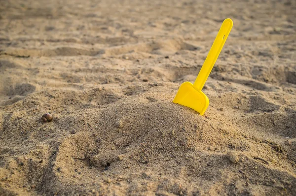 Детская желтая лопата на пляже — стоковое фото